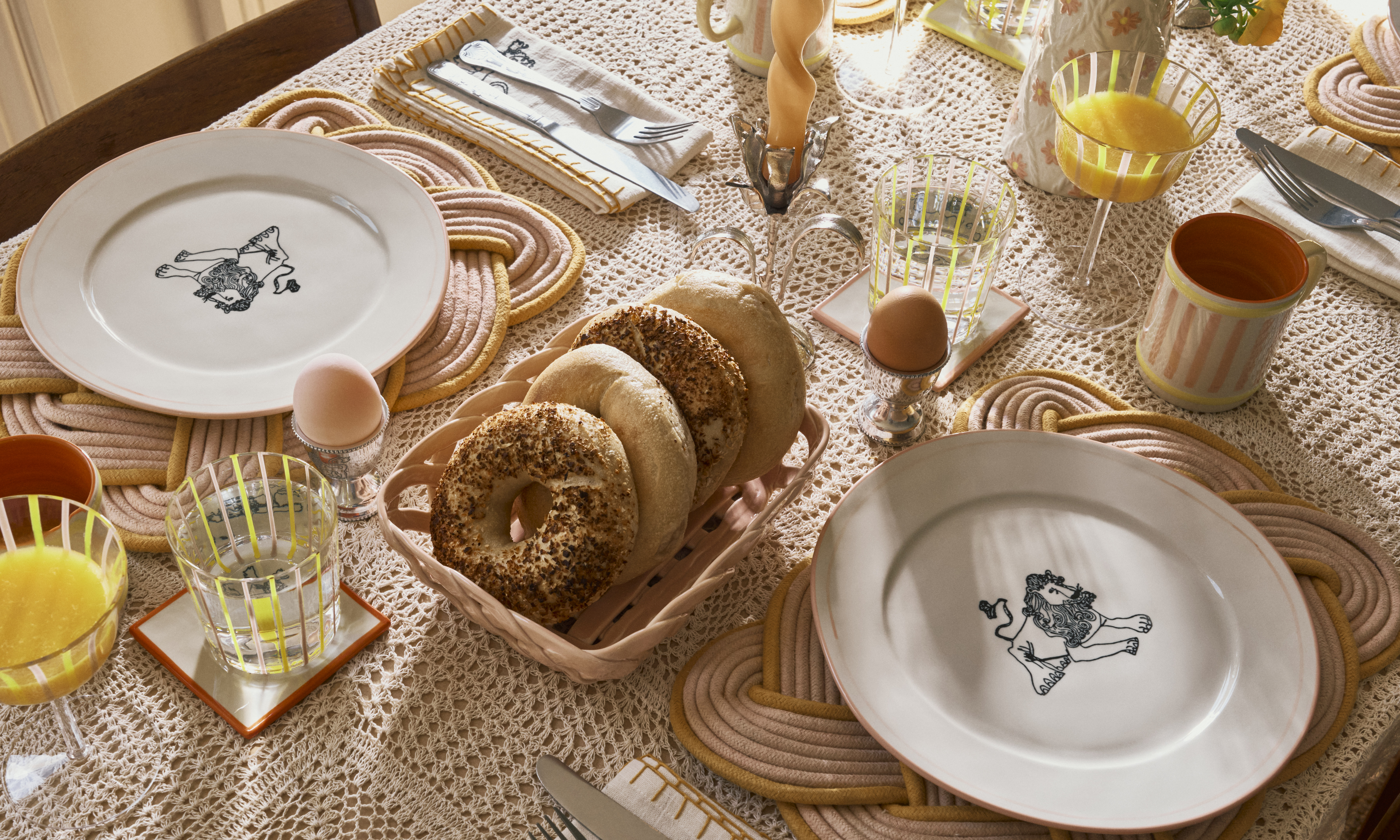 dining table with bagels in a basket and tableware